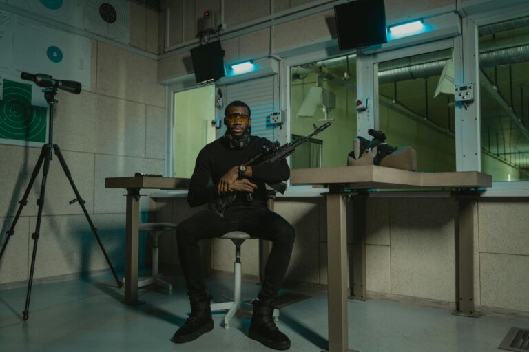 A soldier with a rifle poses confidently indoors at a shooting range.
